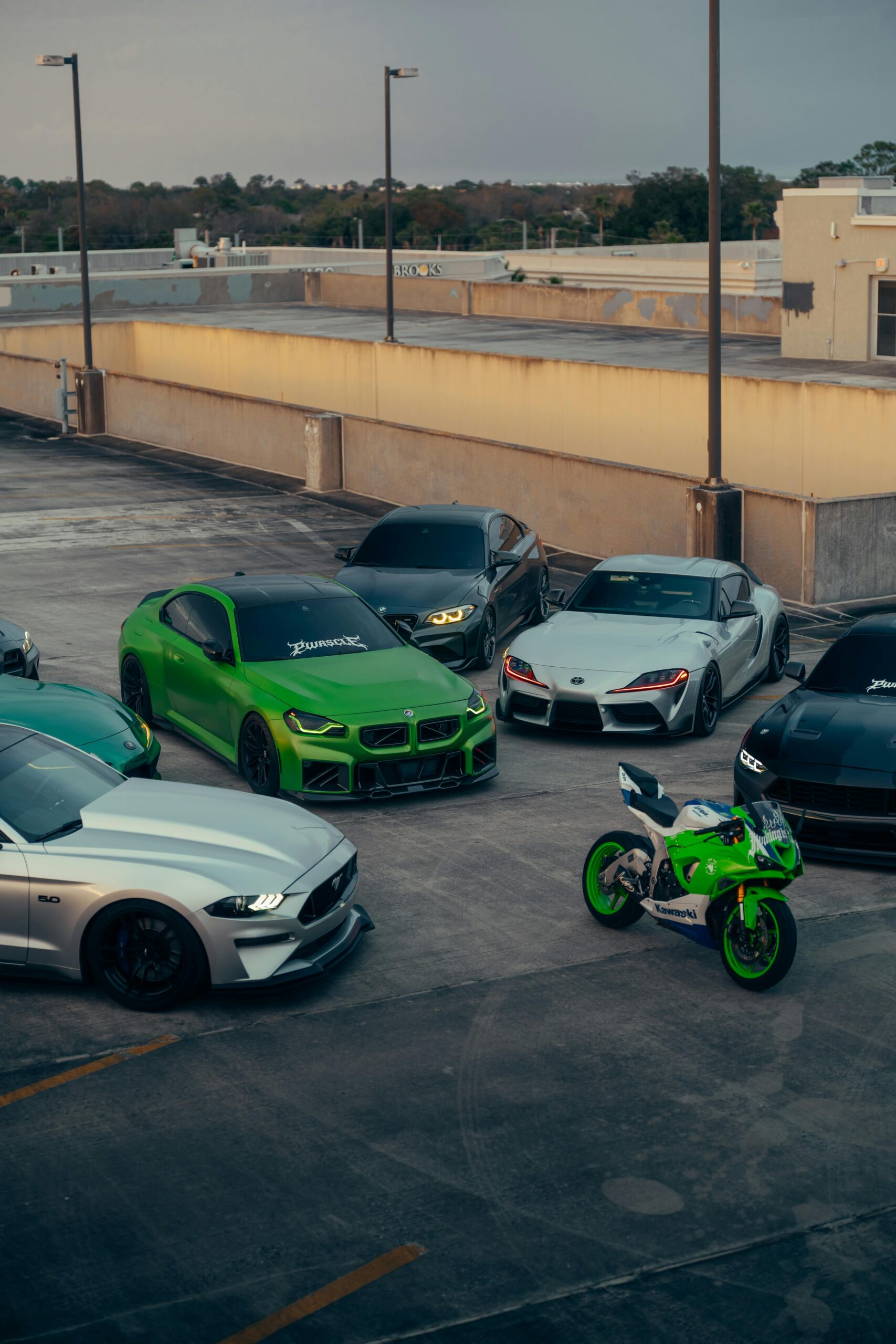 Group of sports cars and a motorcycle in an urban parking lot.